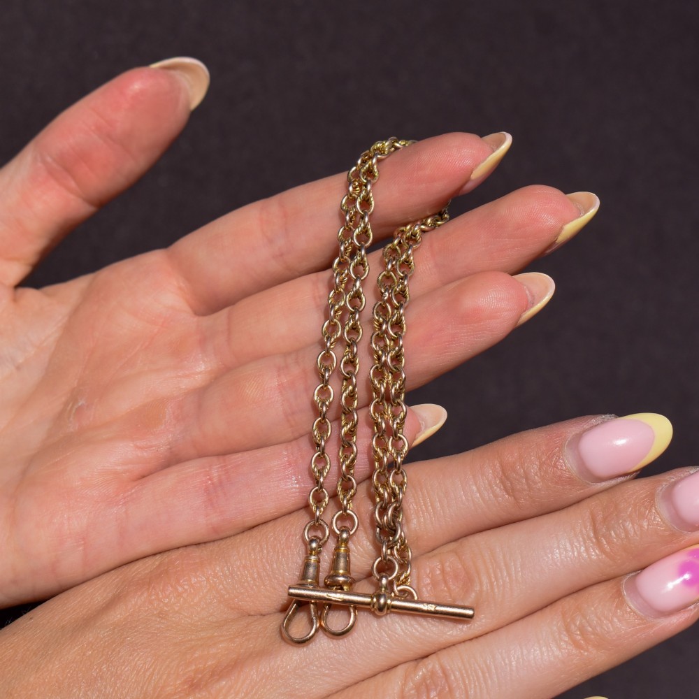 An antique 9ct gold double Albert watch chain featuring love knot links, two swivel clasps, and a central T-bar. View XI