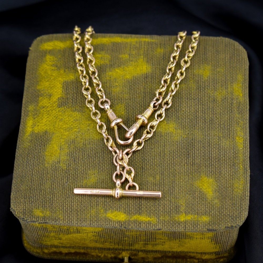 An antique 9ct gold double Albert watch chain featuring love knot links, two swivel clasps, and a central T-bar.