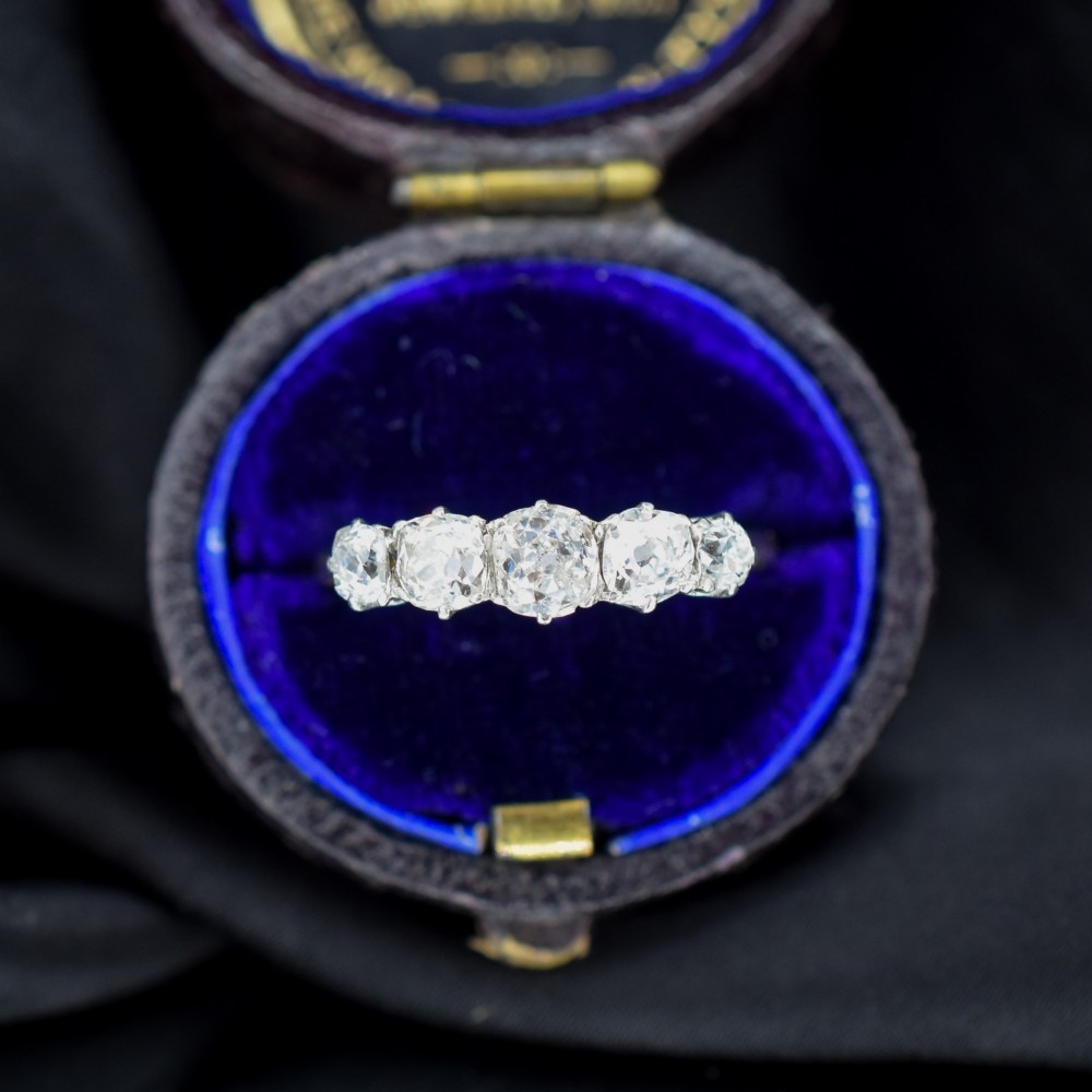An antique five-stone ring featuring five graduated old cut diamonds set in a row mounted on a gold band.
