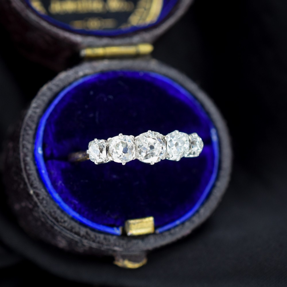 An antique five-stone ring featuring five graduated old cut diamonds set in a row mounted on a gold band. View II