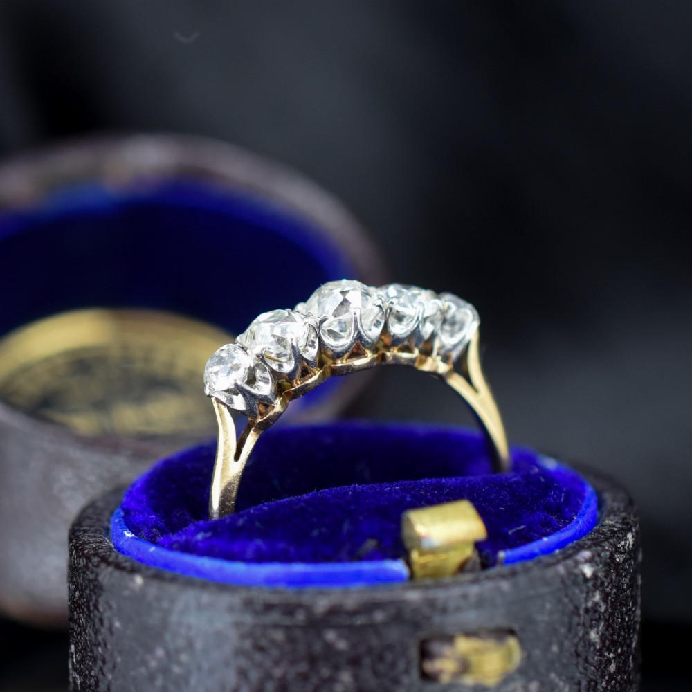An antique five-stone ring featuring five graduated old cut diamonds set in a row mounted on a gold band. View IV