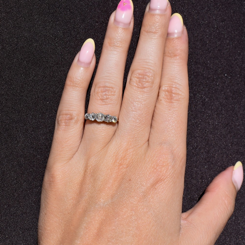 An antique five-stone ring featuring five graduated old cut diamonds set in a row mounted on a gold band. View IX
