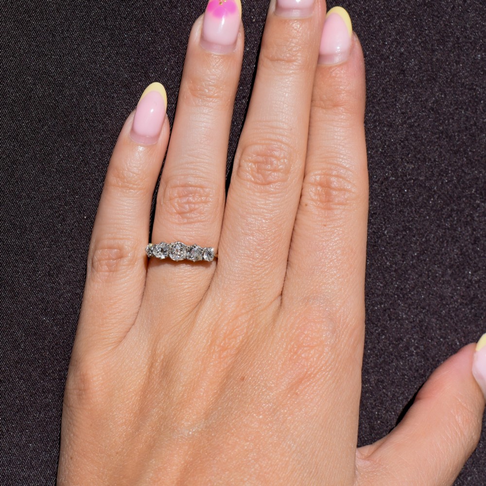 An antique five-stone ring featuring five graduated old cut diamonds set in a row mounted on a gold band. View X