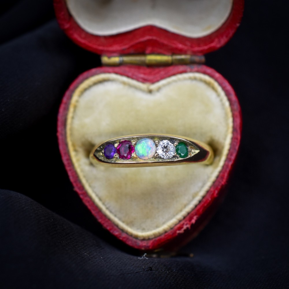 An antique Victorian 15ct yellow gold five-stone ring flush-set with five varied round gemstones across a polished band.