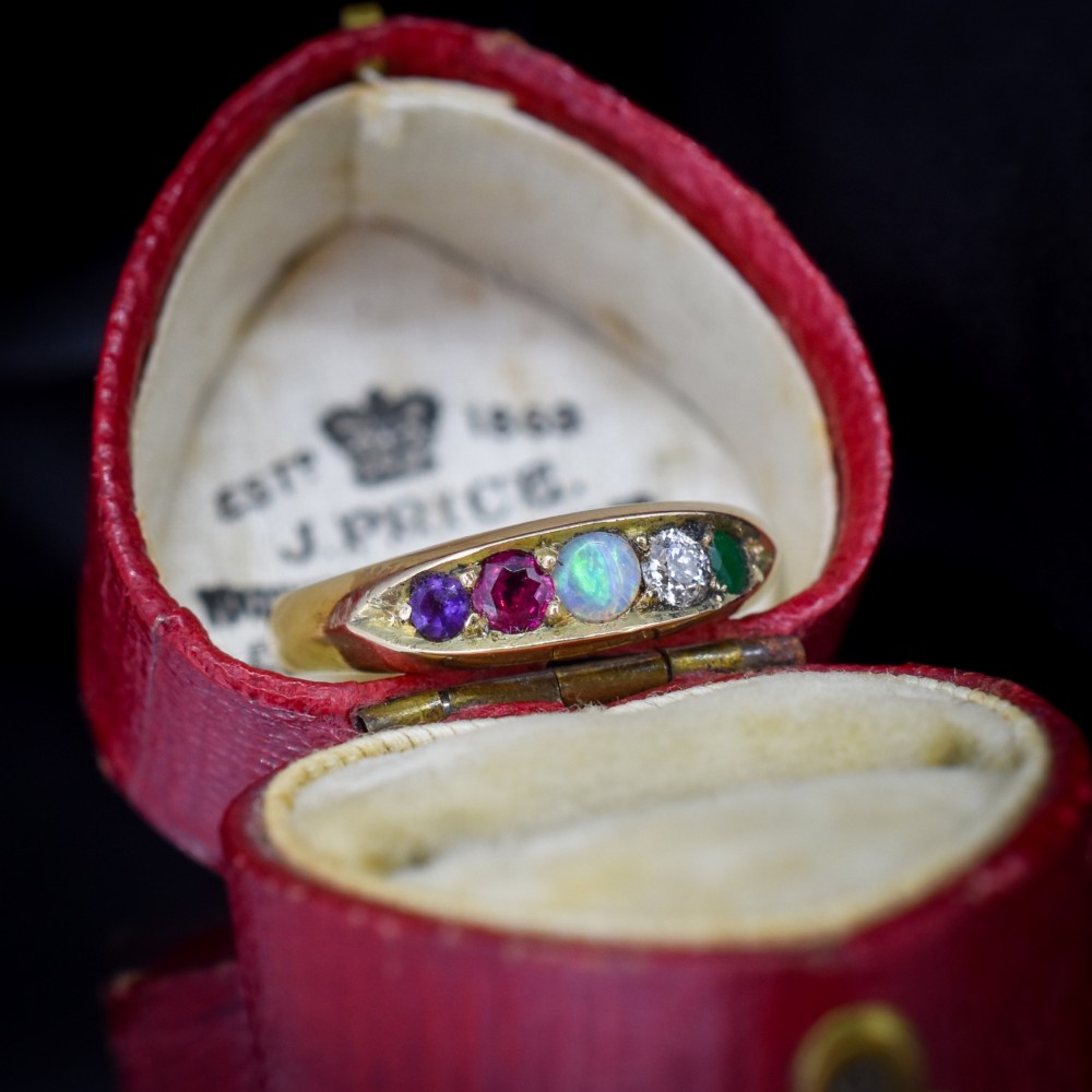 An antique Victorian 15ct yellow gold five-stone ring flush-set with five varied round gemstones across a polished band. View II