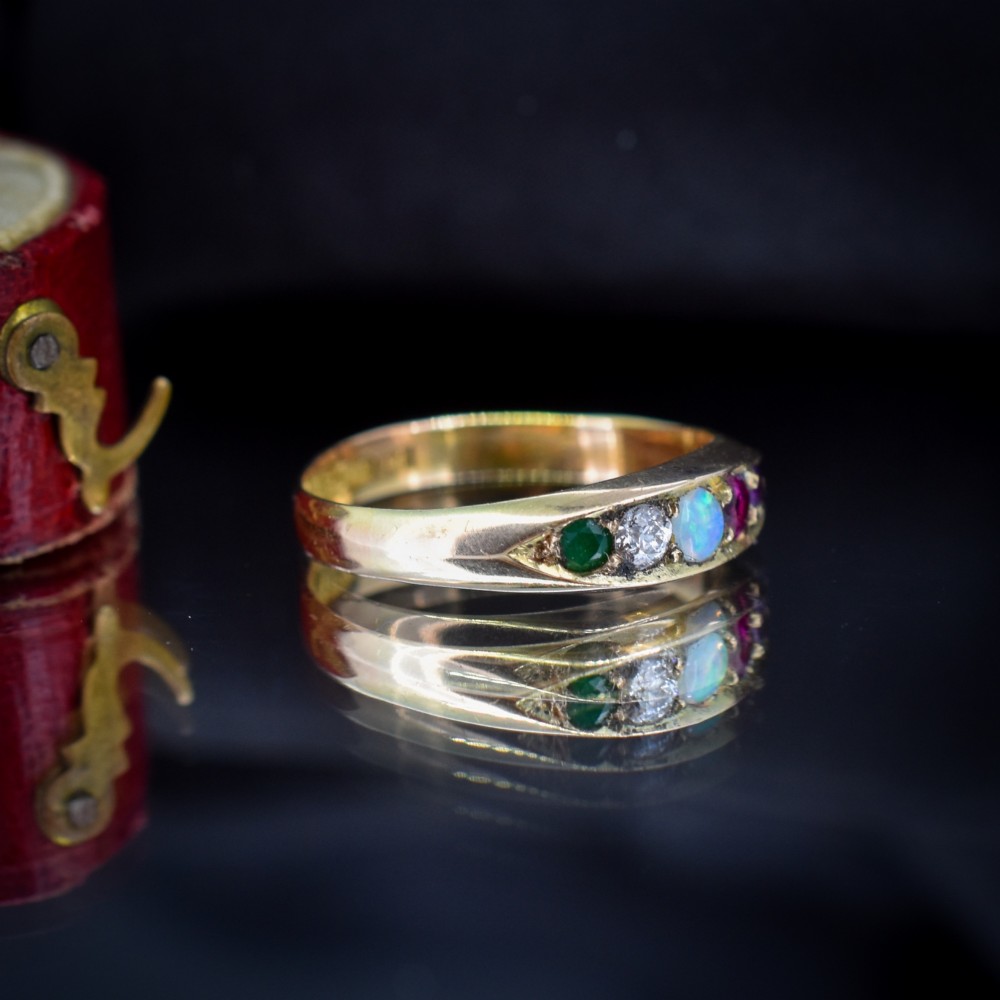 An antique Victorian 15ct yellow gold five-stone ring flush-set with five varied round gemstones across a polished band. View IV
