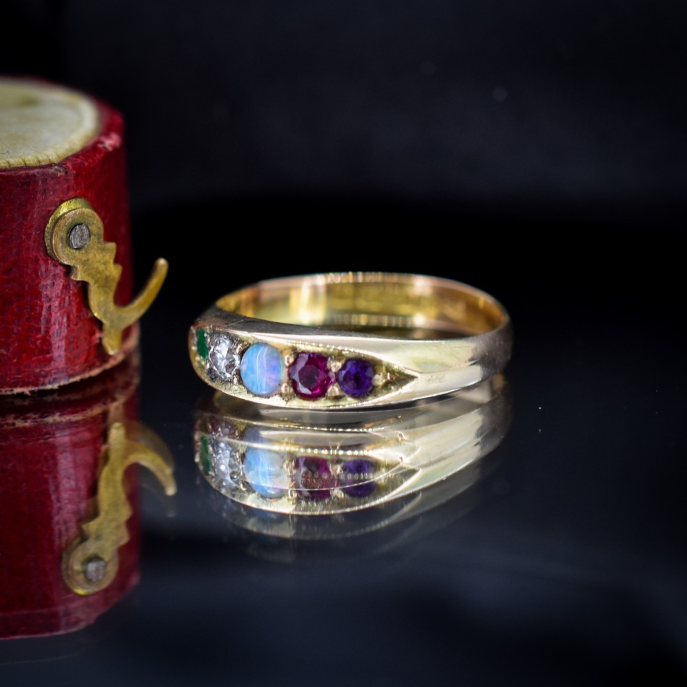 An antique Victorian 15ct yellow gold five-stone ring flush-set with five varied round gemstones across a polished band. View VI