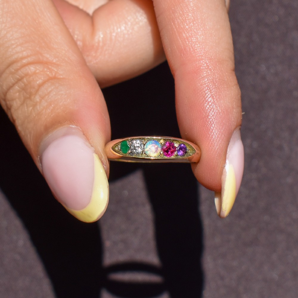 An antique Victorian 15ct yellow gold five-stone ring flush-set with five varied round gemstones across a polished band. View IX