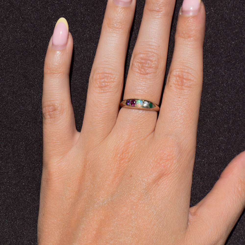An antique Victorian 15ct yellow gold five-stone ring flush-set with five varied round gemstones across a polished band. View X
