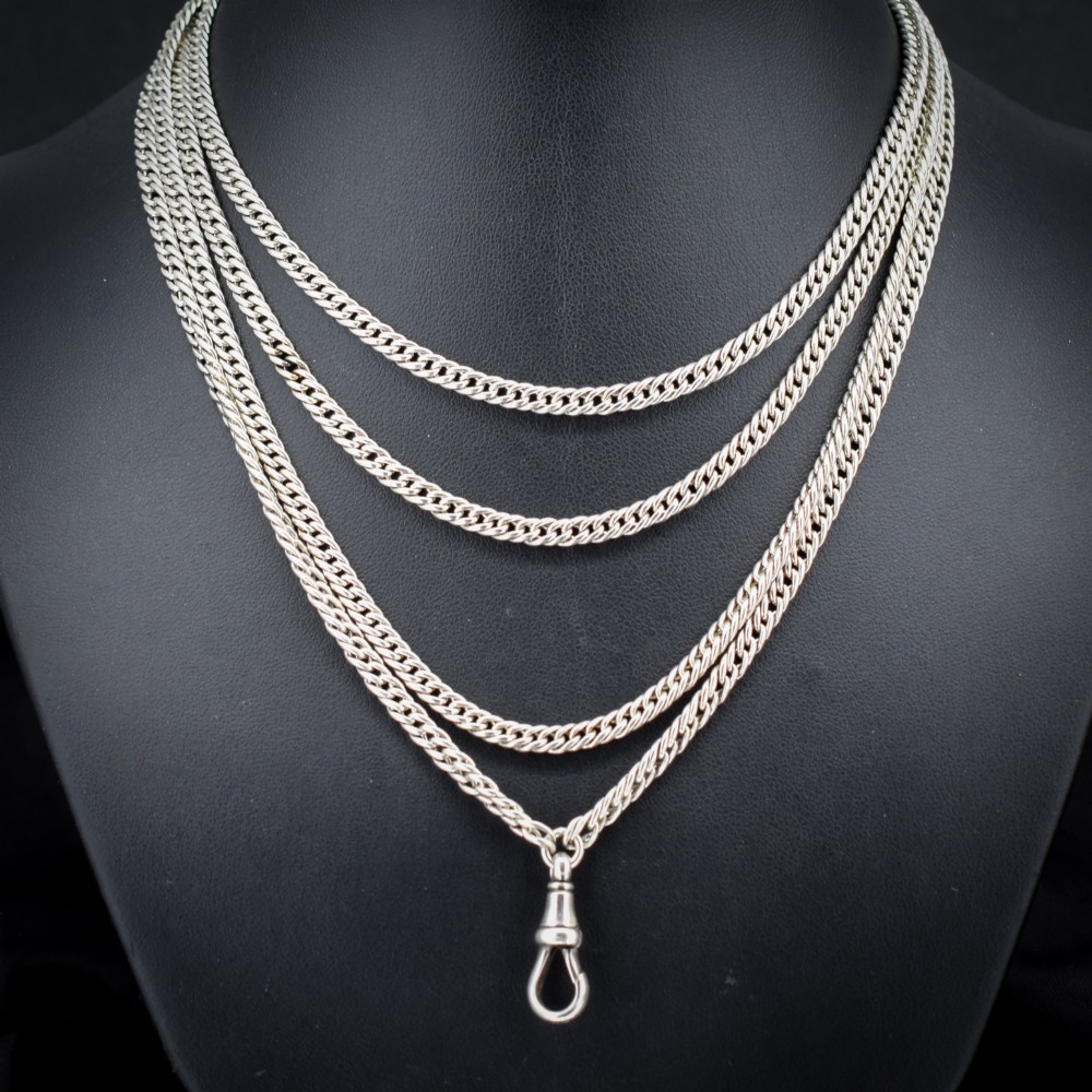 A long sterling silver flat curb link guard chain draped in multiple tiers with a dog clip clasp at the bottom.