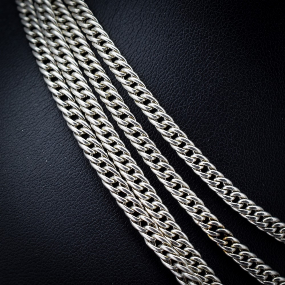 A long sterling silver flat curb link guard chain draped in multiple tiers with a dog clip clasp at the bottom. View IV