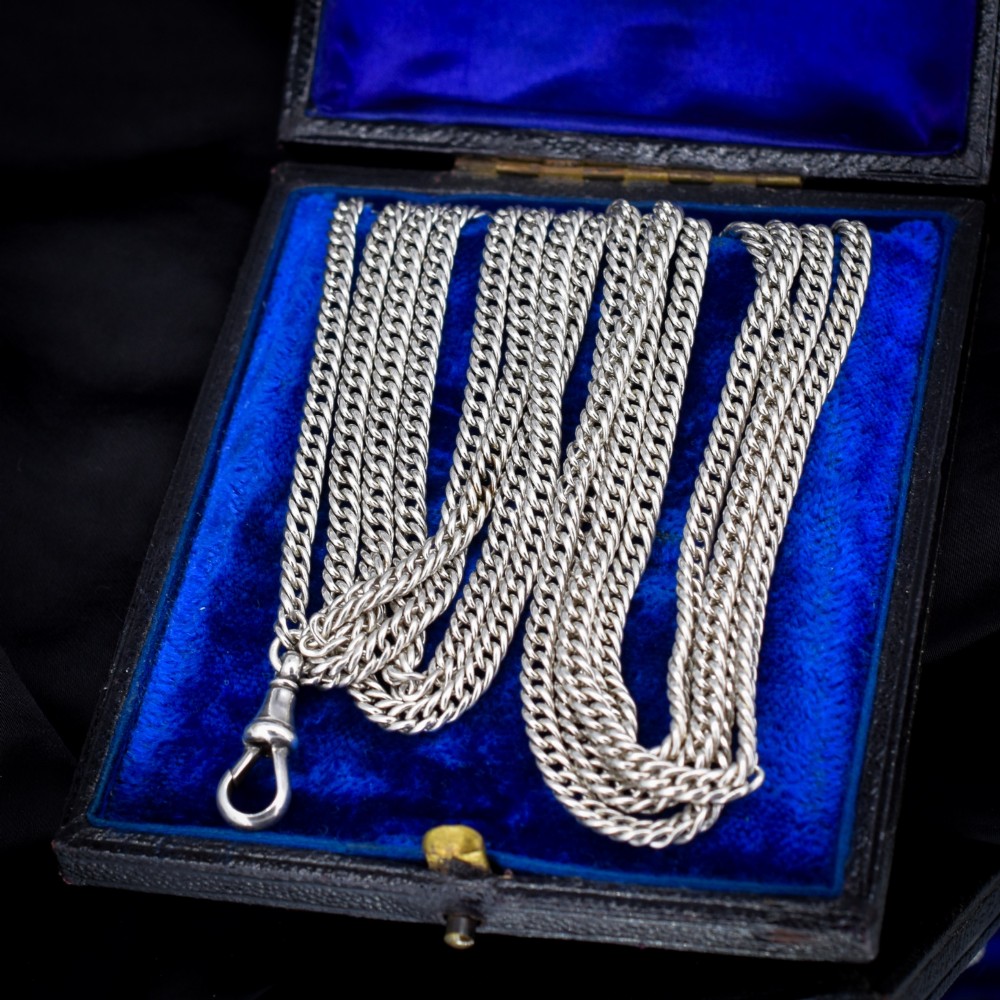 A long sterling silver flat curb link guard chain draped in multiple tiers with a dog clip clasp at the bottom. View V