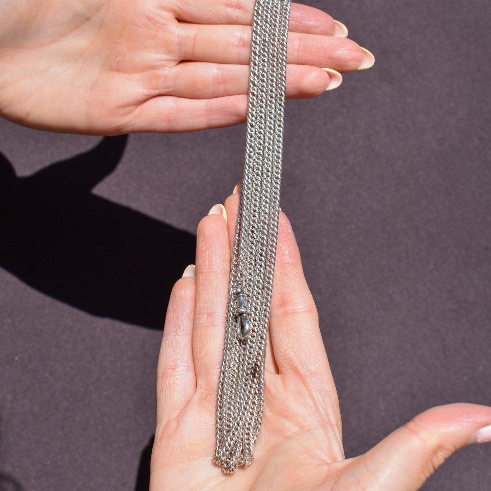 A long sterling silver flat curb link guard chain draped in multiple tiers with a dog clip clasp at the bottom. View X