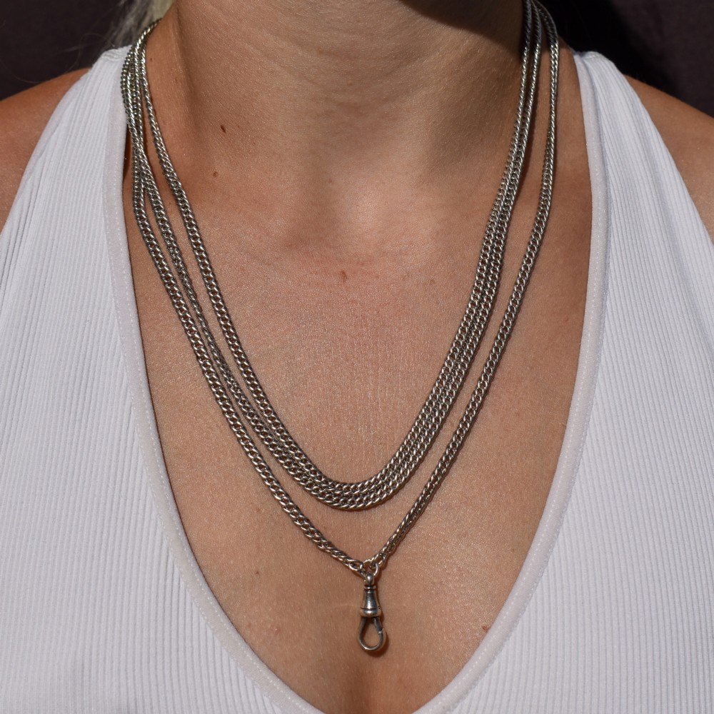 A long sterling silver flat curb link guard chain draped in multiple tiers with a dog clip clasp at the bottom. View XII