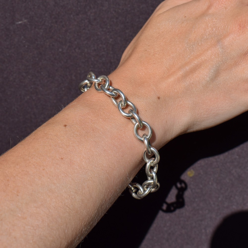 A sterling silver link bracelet composed of interlocking oval cable links with a bolt ring clasp. View VII
