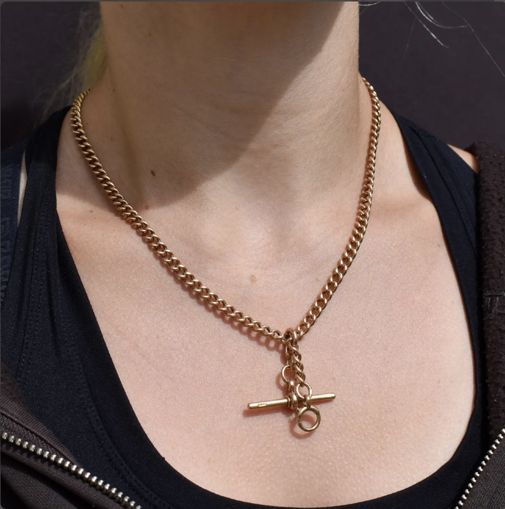 An antique 15ct yellow gold Albert chain necklace featuring curb links, a T-bar drop, a bolt ring, and a dog clip clasp. View V