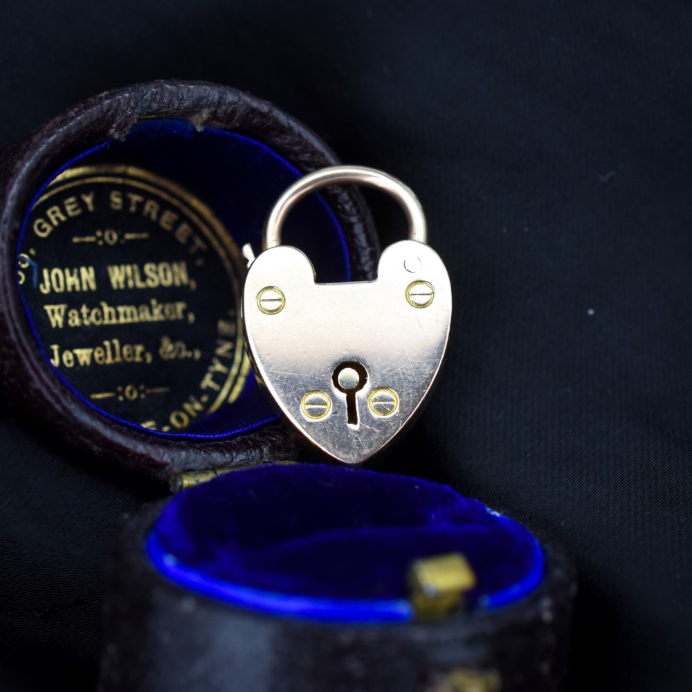 An antique 9ct gold heart-shaped padlock pendant with a smooth polished finish, central keyhole detail, and visible screw head accents.