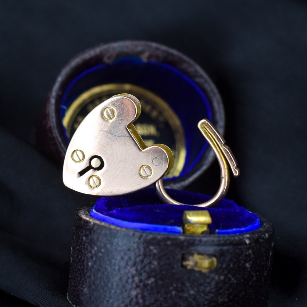 An antique 9ct gold heart-shaped padlock pendant with a smooth polished finish, central keyhole detail, and visible screw head accents. View V