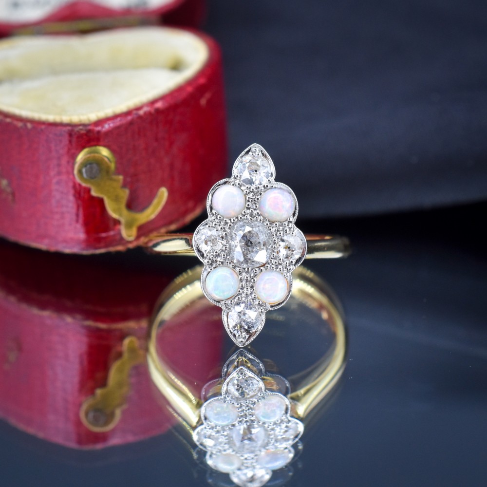 An Edwardian 18ct gold and platinum navette cluster ring featuring a central old cut diamond bordered by four cabochon opals and additional diamond accents. View IV