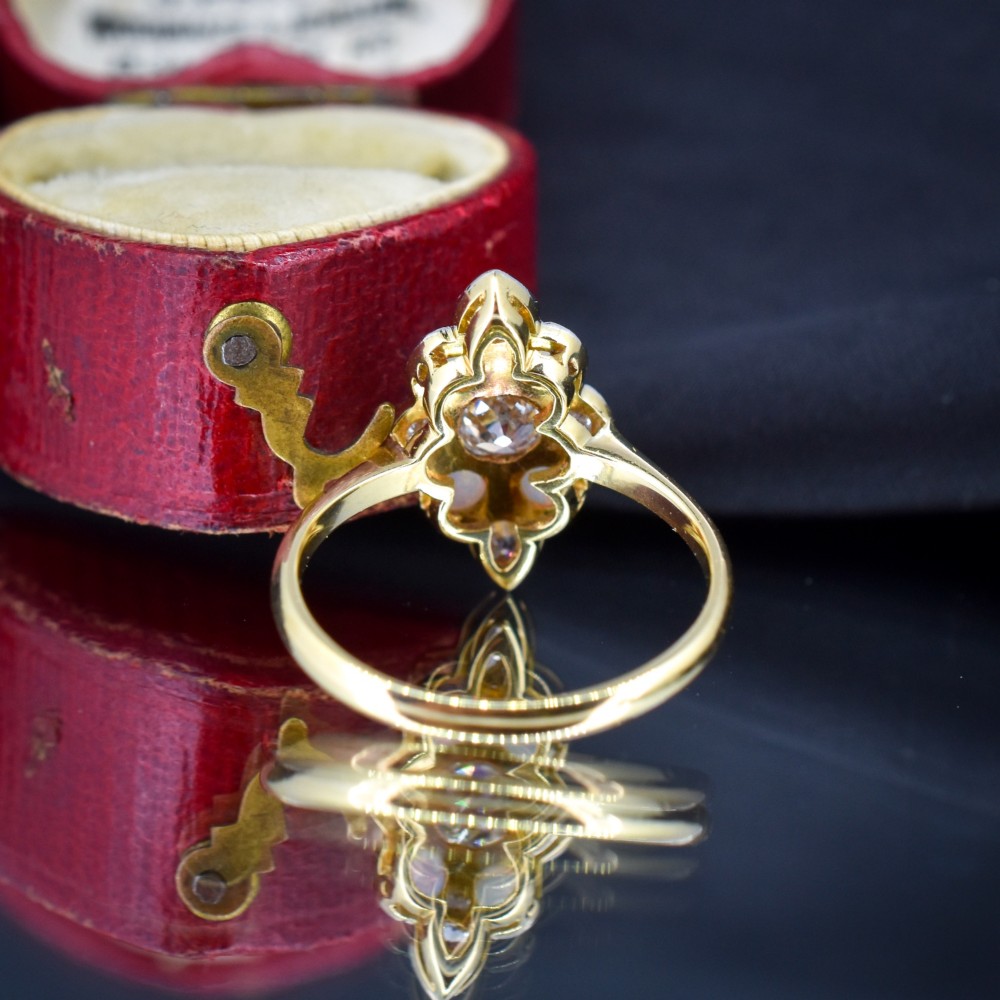 An Edwardian 18ct gold and platinum navette cluster ring featuring a central old cut diamond bordered by four cabochon opals and additional diamond accents. View VI