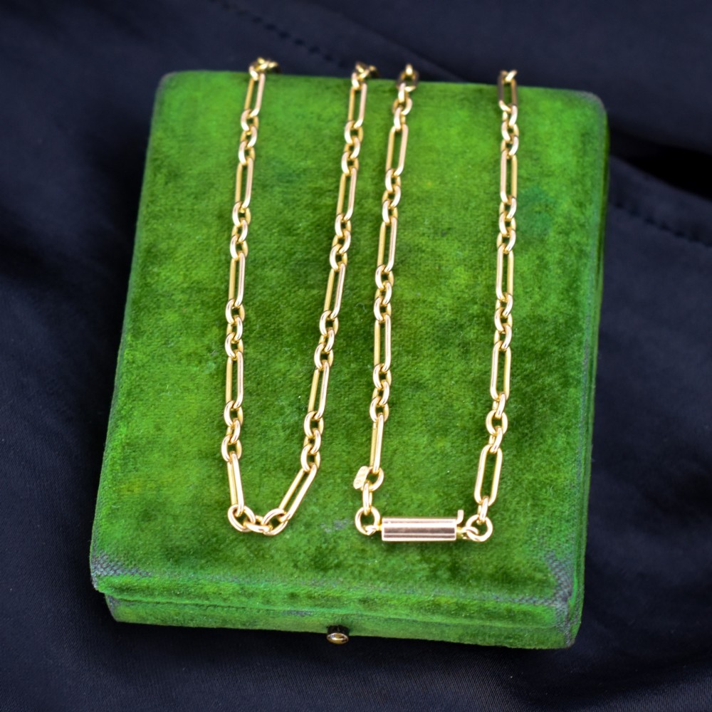 An antique 15ct yellow gold chain featuring alternating long trombone links and short oval links with a barrel clasp.