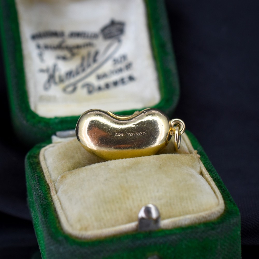 A smooth, polished 9ct yellow gold bean-shaped charm with an attached suspension jump ring. View II