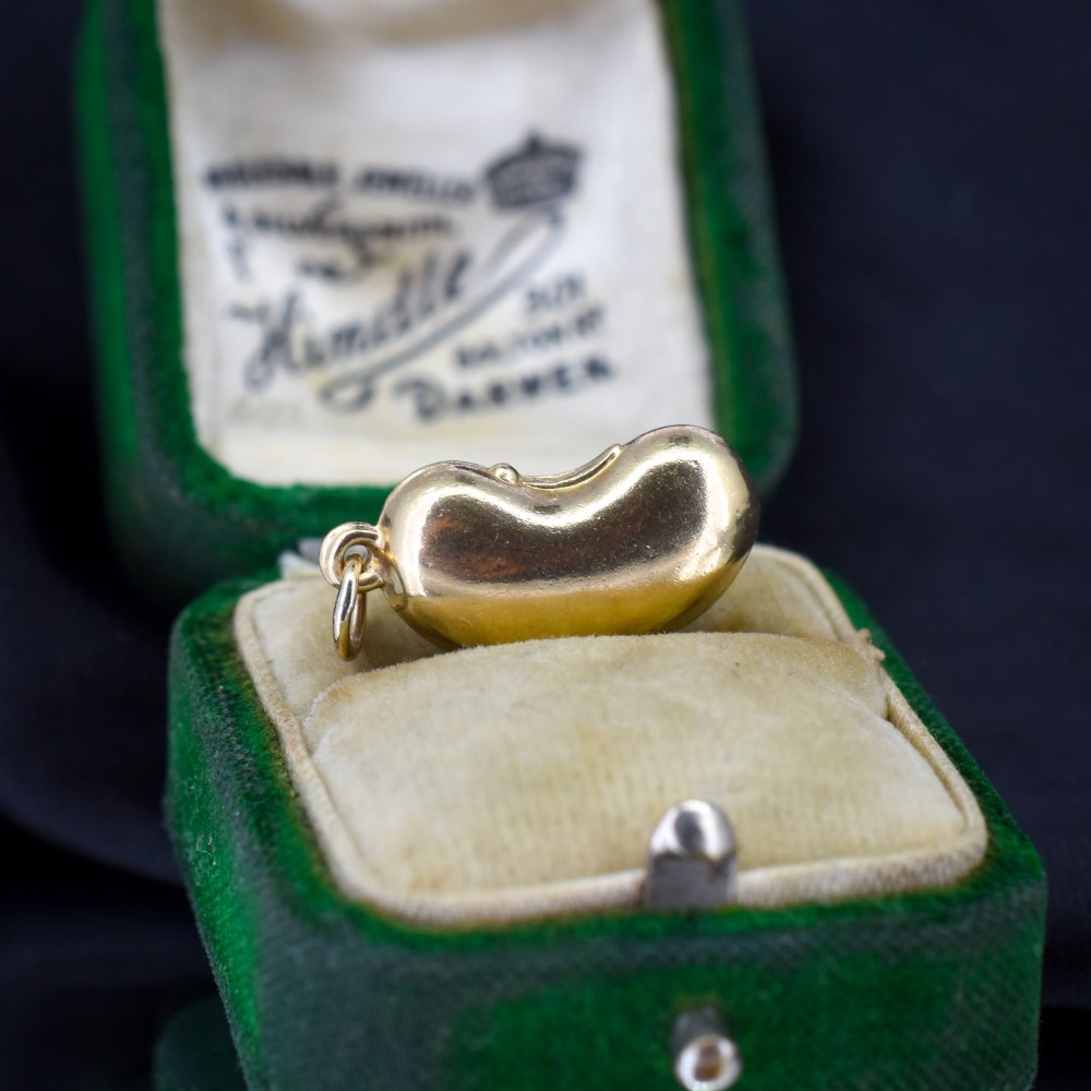 A smooth, polished 9ct yellow gold bean-shaped charm with an attached suspension jump ring.