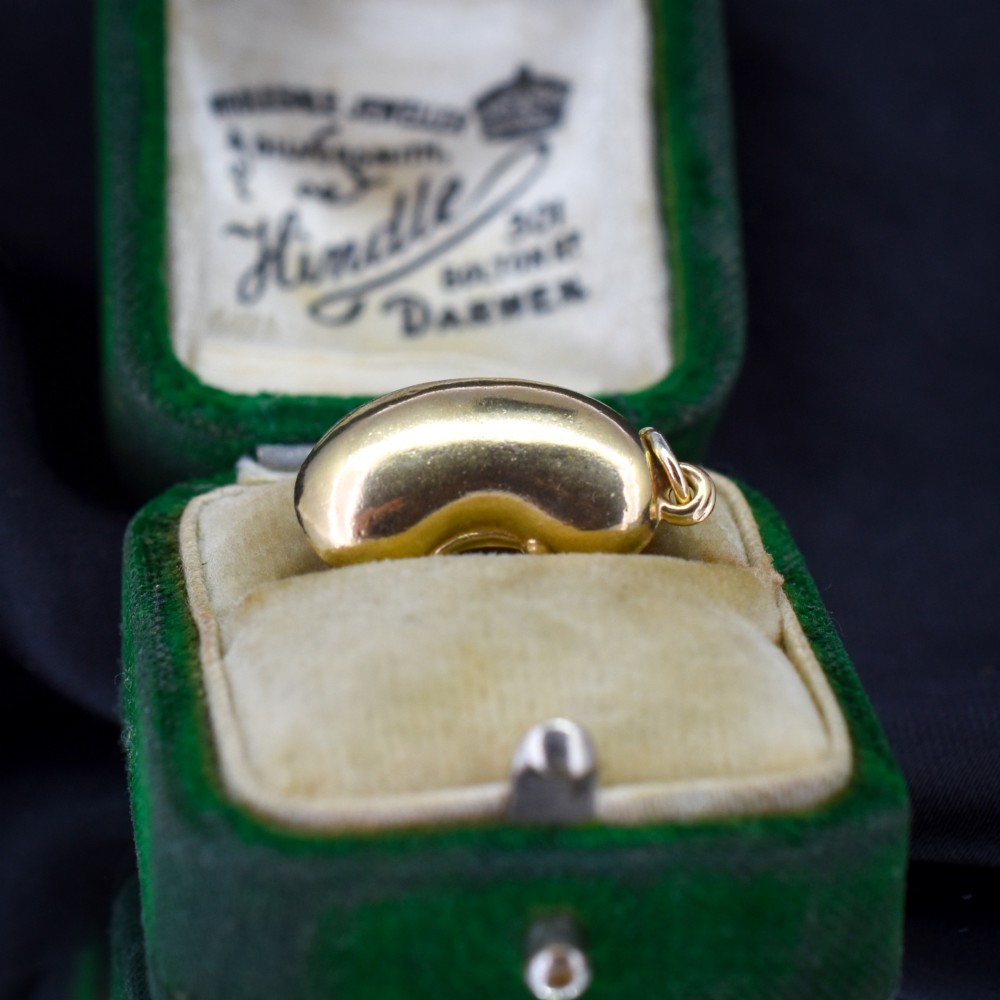 A smooth, polished 9ct yellow gold bean-shaped charm with an attached suspension jump ring. View V