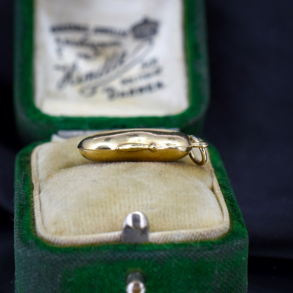 A smooth, polished 9ct yellow gold bean-shaped charm with an attached suspension jump ring. View VI