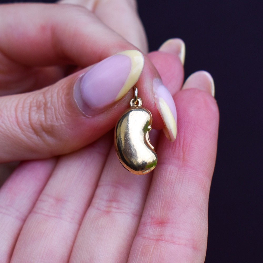 A smooth, polished 9ct yellow gold bean-shaped charm with an attached suspension jump ring. View VIII
