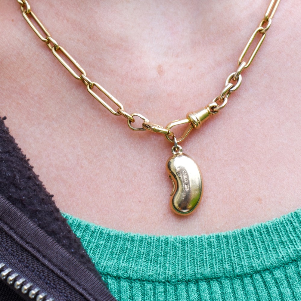 A smooth, polished 9ct yellow gold bean-shaped charm with an attached suspension jump ring. View IX