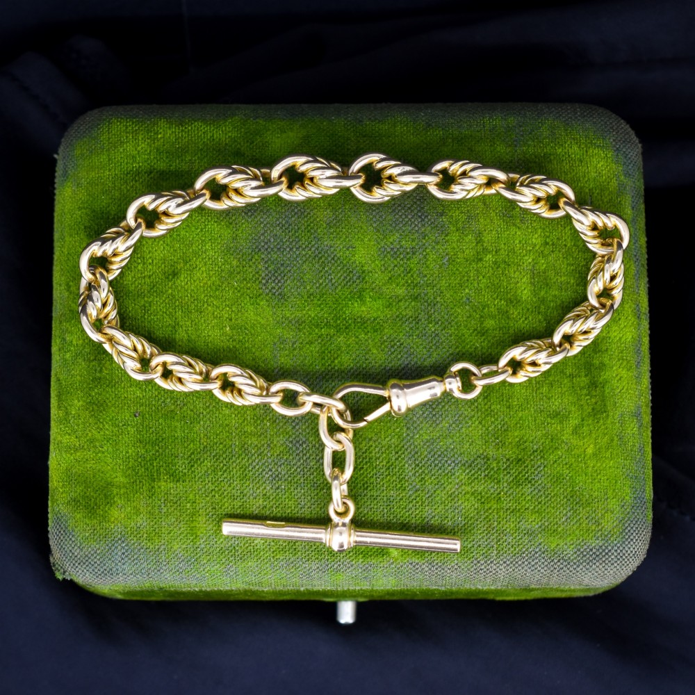 An antique 9ct yellow gold love knot chain bracelet featuring a swivel clasp and suspended T-bar detail.