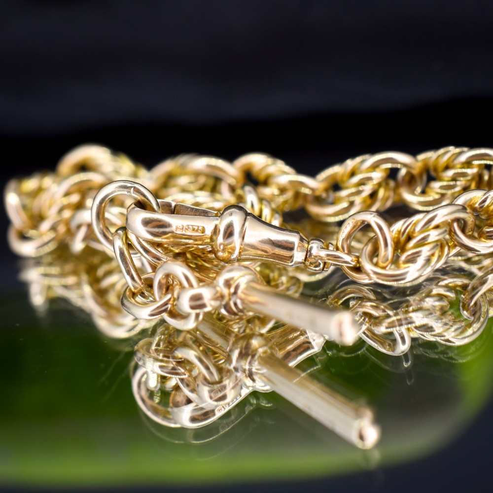 An antique 9ct yellow gold love knot chain bracelet featuring a swivel clasp and suspended T-bar detail. View V