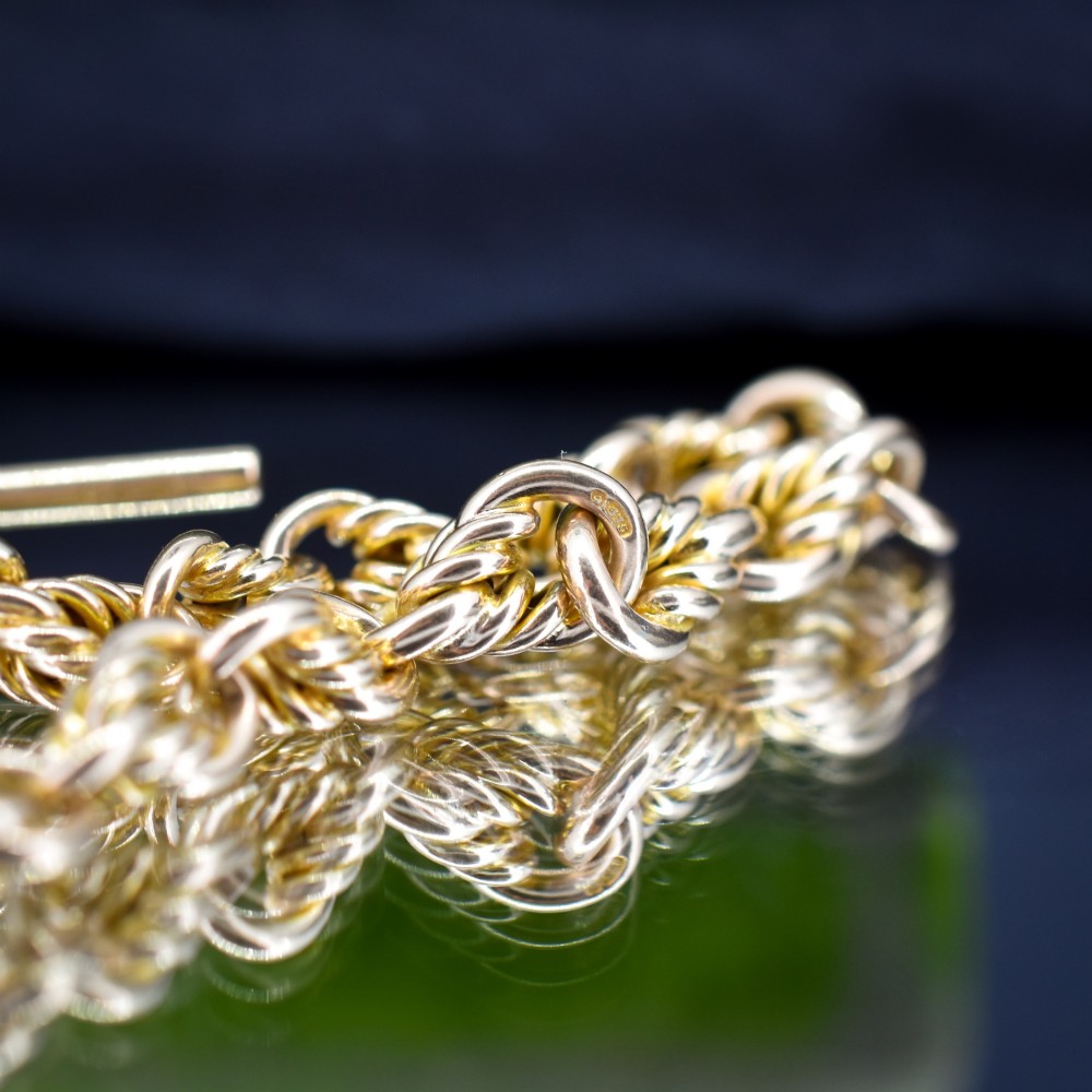 An antique 9ct yellow gold love knot chain bracelet featuring a swivel clasp and suspended T-bar detail. View VI