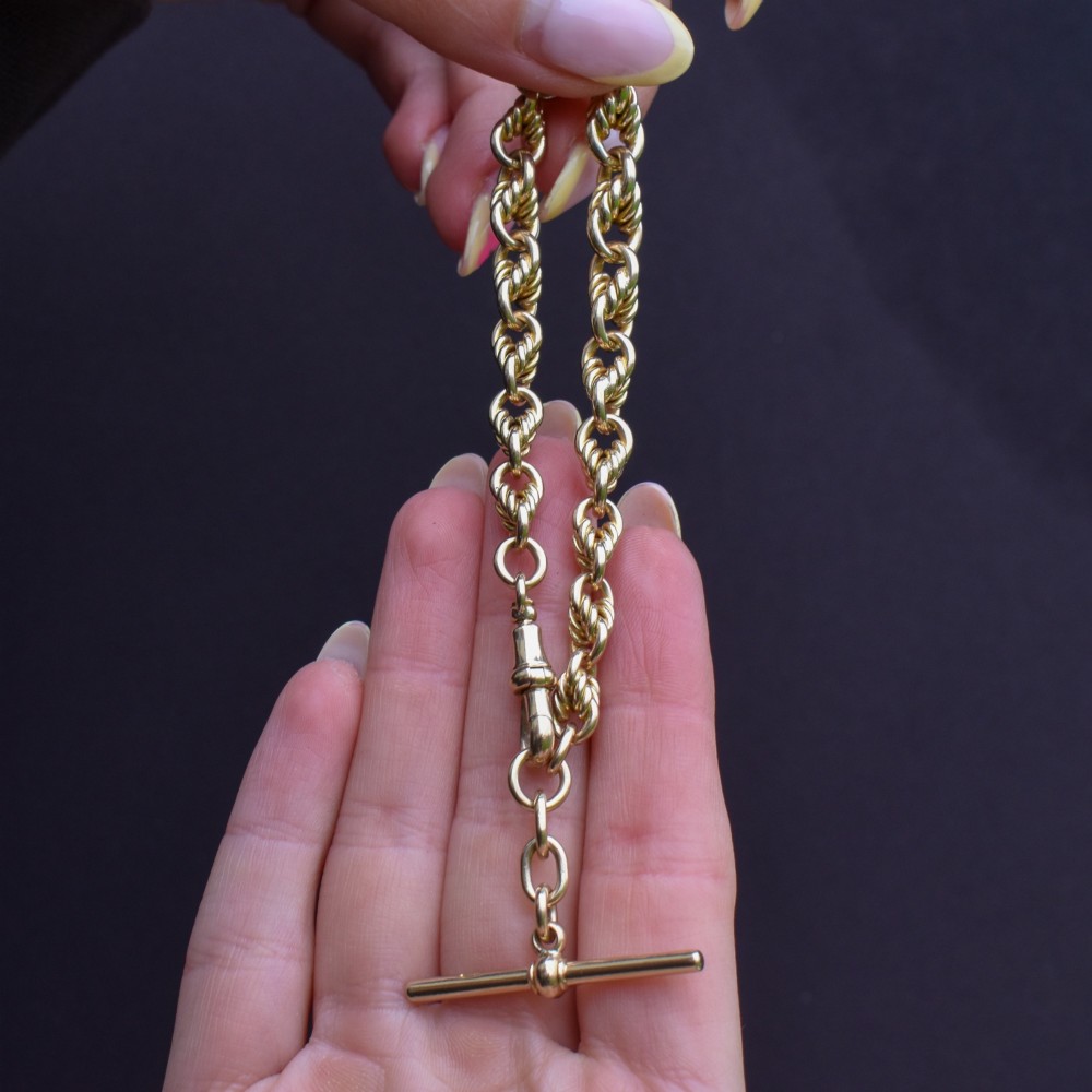 An antique 9ct yellow gold love knot chain bracelet featuring a swivel clasp and suspended T-bar detail. View VII