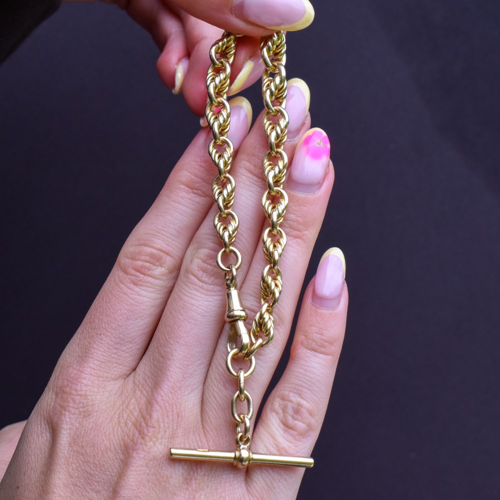 An antique 9ct yellow gold love knot chain bracelet featuring a swivel clasp and suspended T-bar detail. View VIII