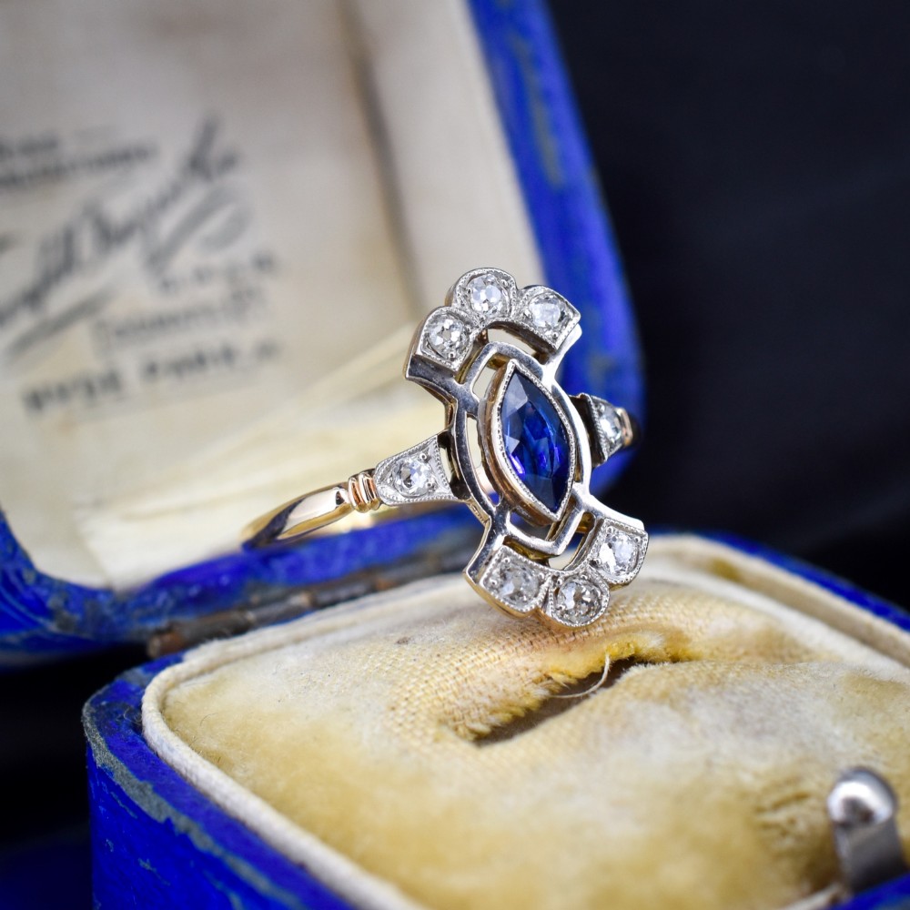 An Art Deco gold ring featuring a central marquise-cut blue sapphire framed by an intricate openwork diamond-set navette halo. View III