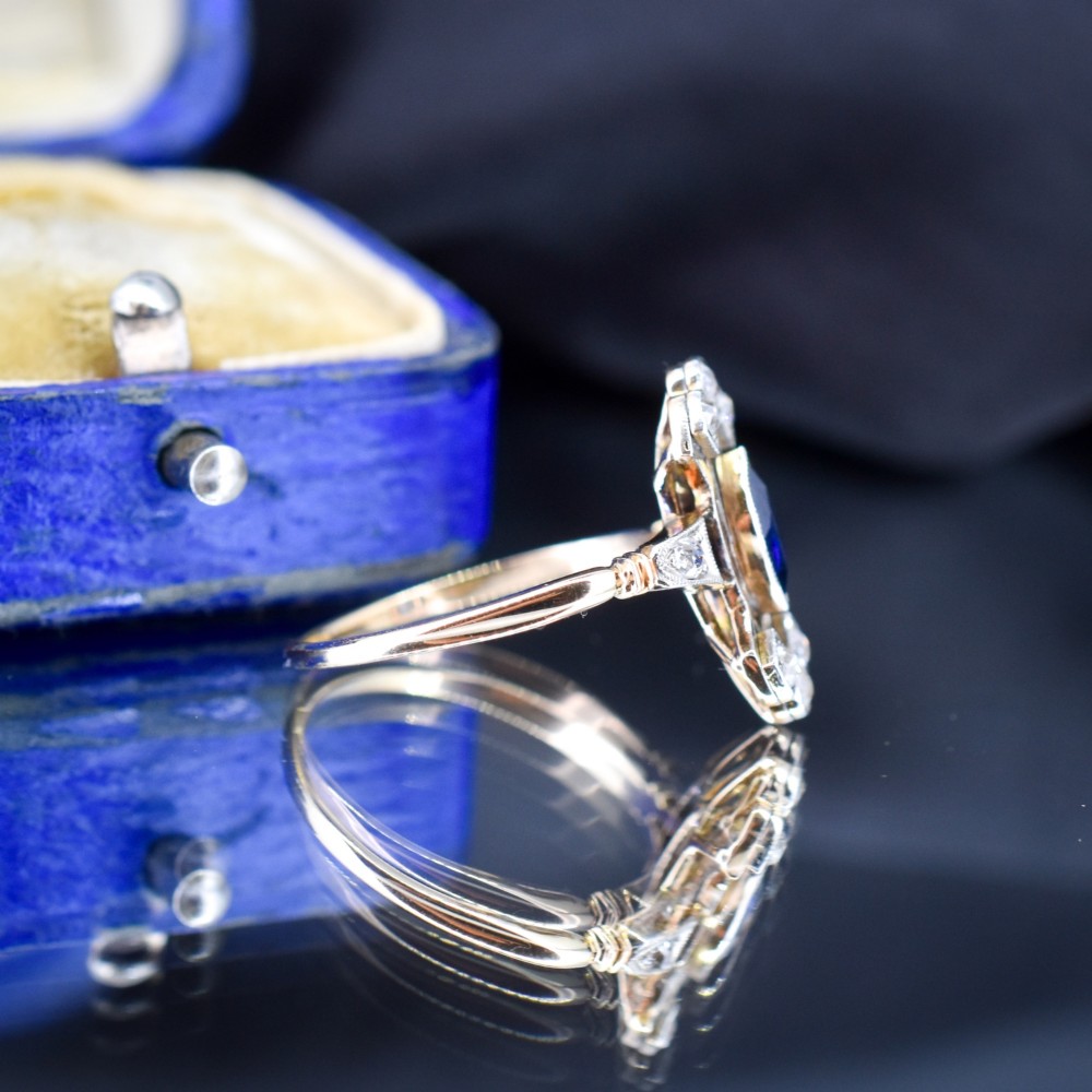 An Art Deco gold ring featuring a central marquise-cut blue sapphire framed by an intricate openwork diamond-set navette halo. View V