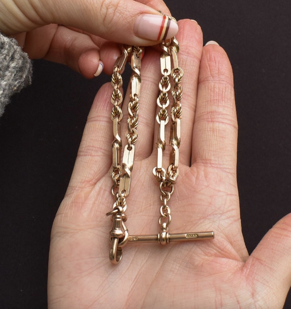 A 9ct yellow gold double Albert chain necklace with love knot links and a central T-bar drop displayed on a black bust. View III