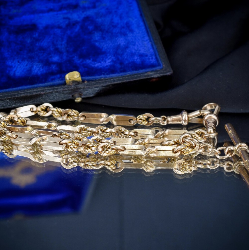 A 9ct yellow gold double Albert chain necklace with love knot links and a central T-bar drop displayed on a black bust. View VI