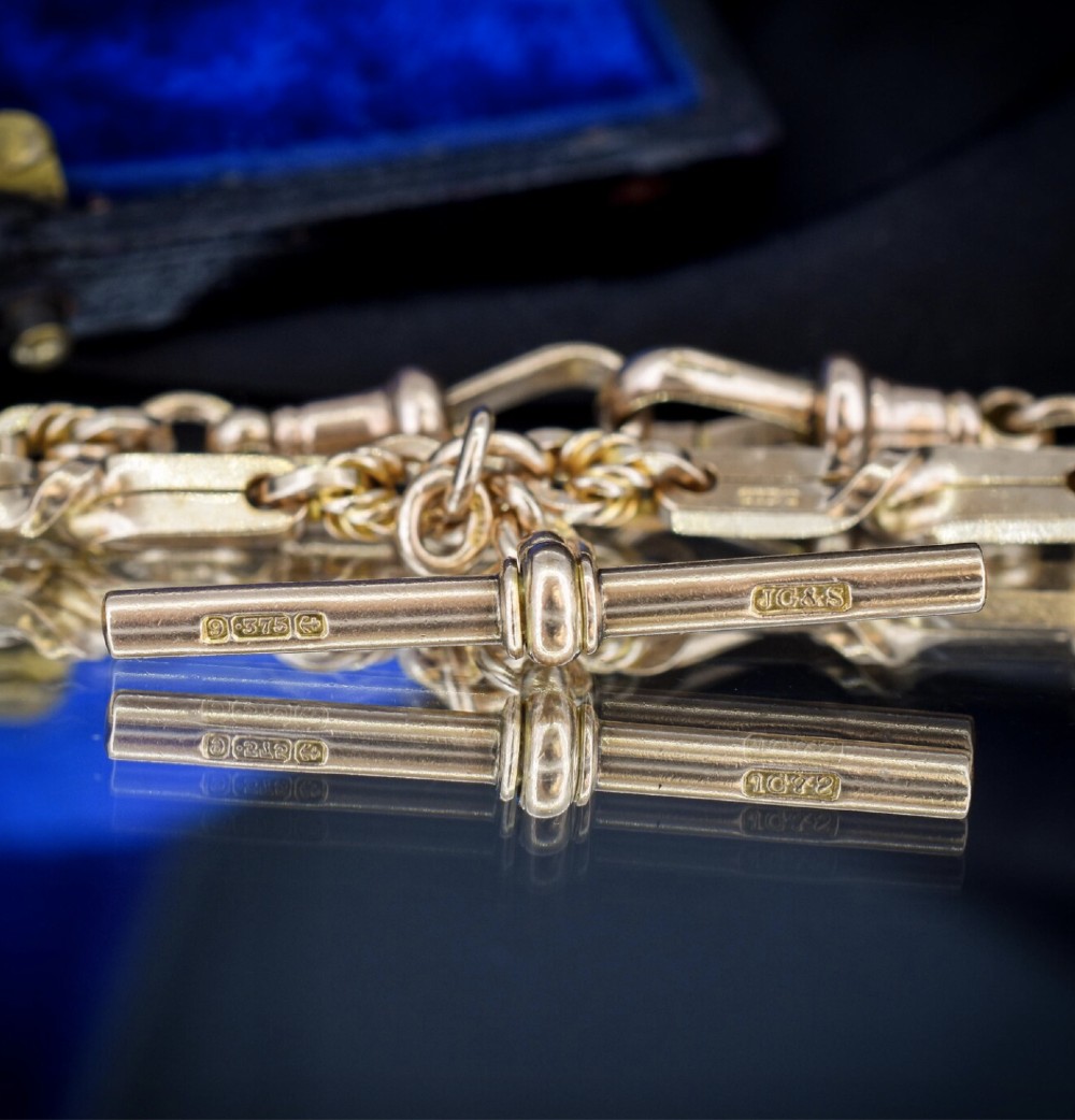 A 9ct yellow gold double Albert chain necklace with love knot links and a central T-bar drop displayed on a black bust. View VII