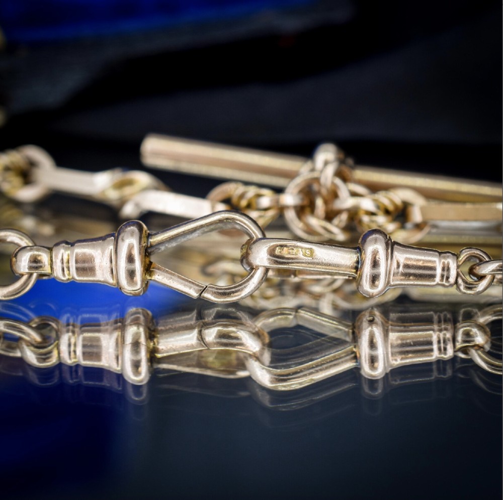 A 9ct yellow gold double Albert chain necklace with love knot links and a central T-bar drop displayed on a black bust. View VIII