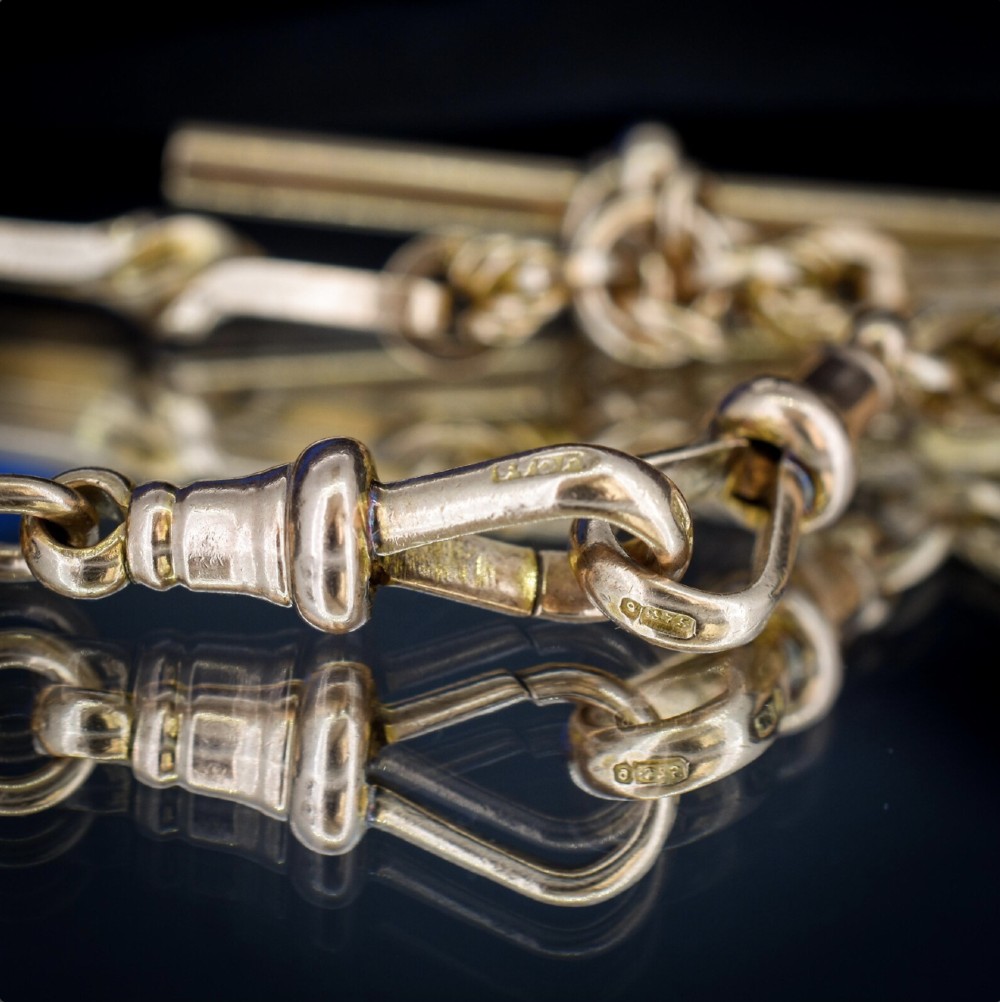 A 9ct yellow gold double Albert chain necklace with love knot links and a central T-bar drop displayed on a black bust. View IX