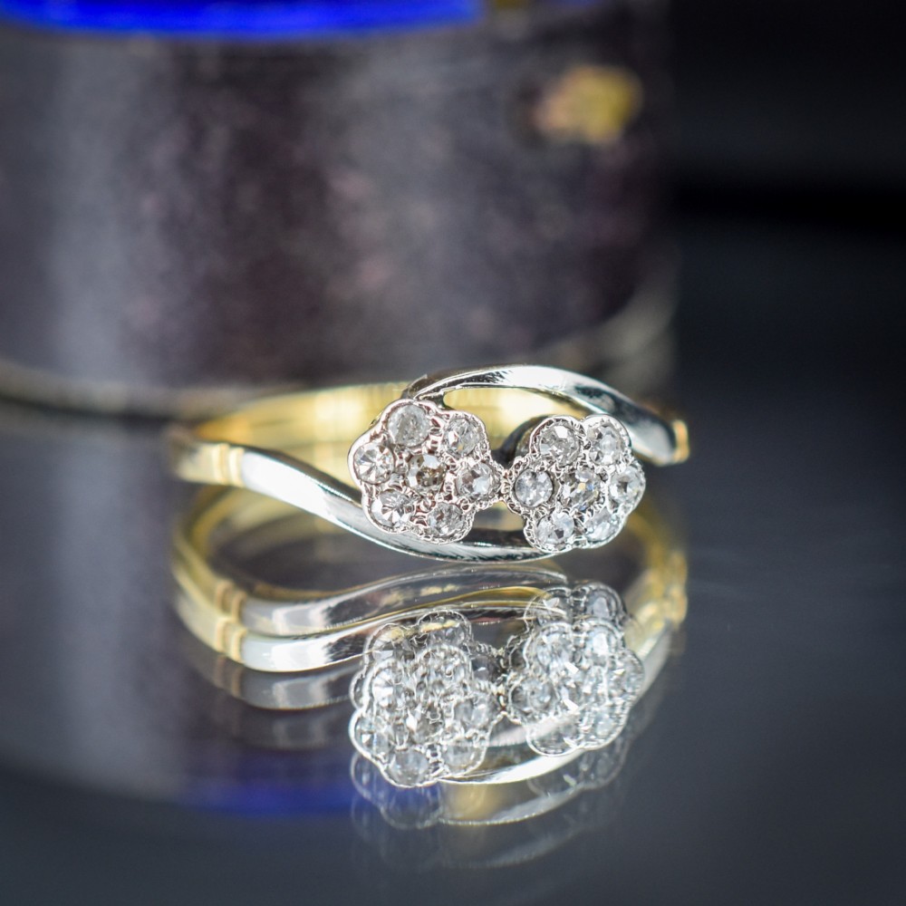 An antique 18ct yellow gold crossover ring featuring two diamond cluster flowers set in white metal on sweeping twist shoulders. View II