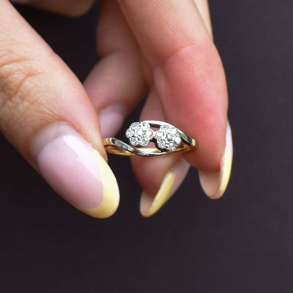 An antique 18ct yellow gold crossover ring featuring two diamond cluster flowers set in white metal on sweeping twist shoulders. View VIII