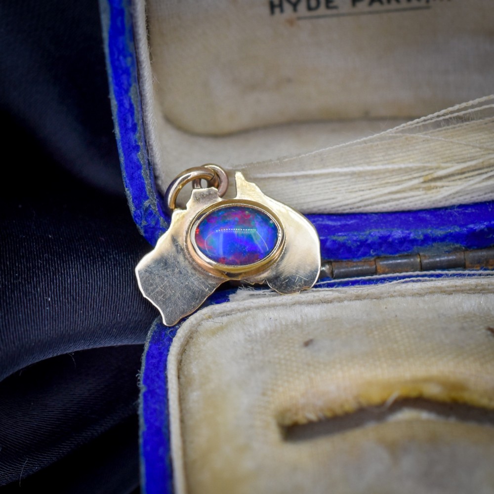 A 9ct yellow gold pendant in the shape of Australia, featuring a central bezel-set oval black opal triplet with blue and violet play-of-colour.