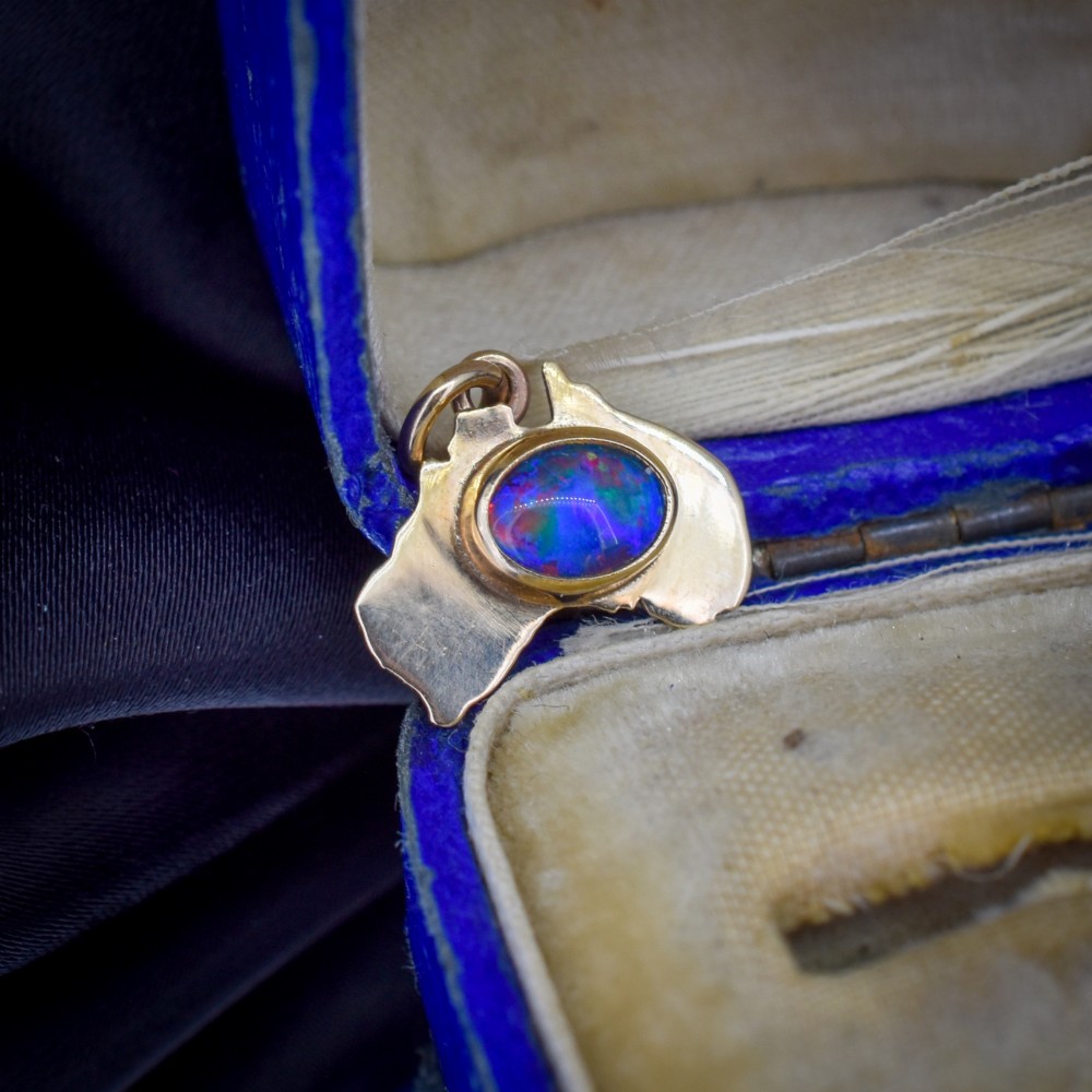 A 9ct yellow gold pendant in the shape of Australia, featuring a central bezel-set oval black opal triplet with blue and violet play-of-colour. View II