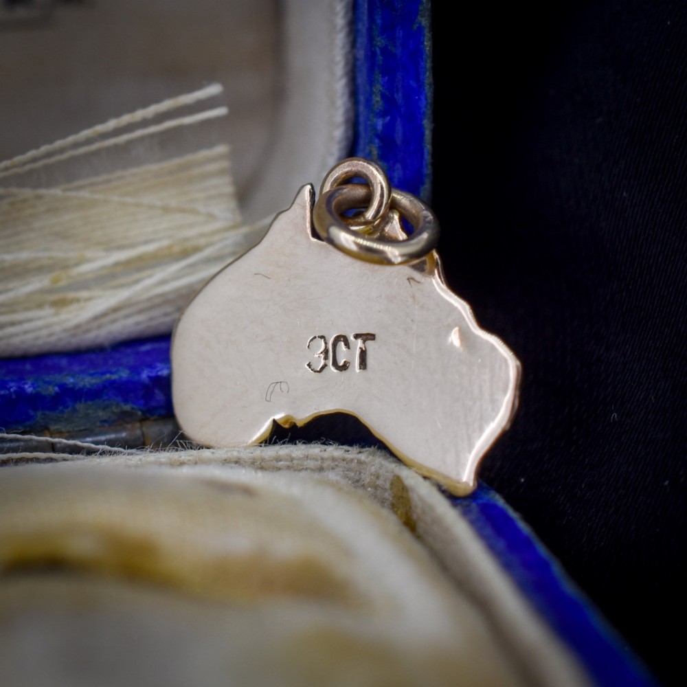 A 9ct yellow gold pendant in the shape of Australia, featuring a central bezel-set oval black opal triplet with blue and violet play-of-colour. View IV