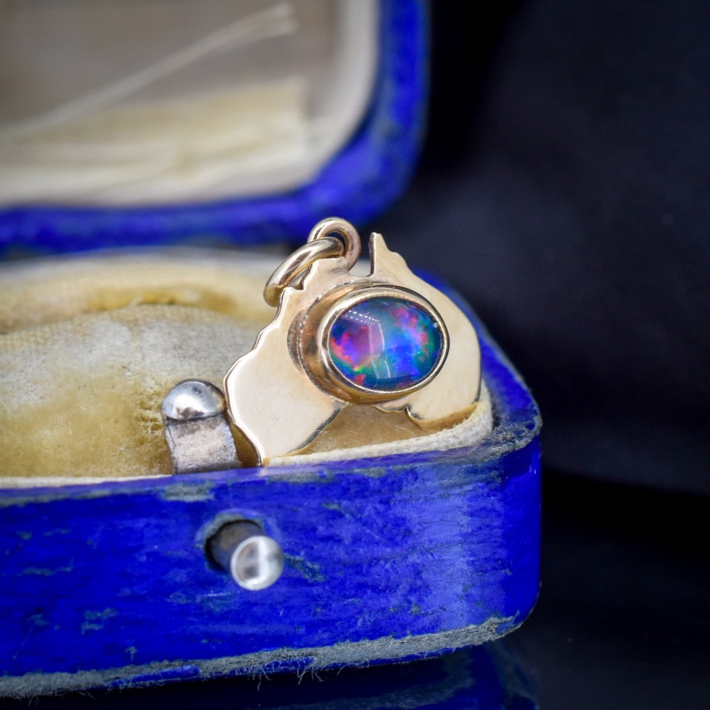 A 9ct yellow gold pendant in the shape of Australia, featuring a central bezel-set oval black opal triplet with blue and violet play-of-colour. View VII