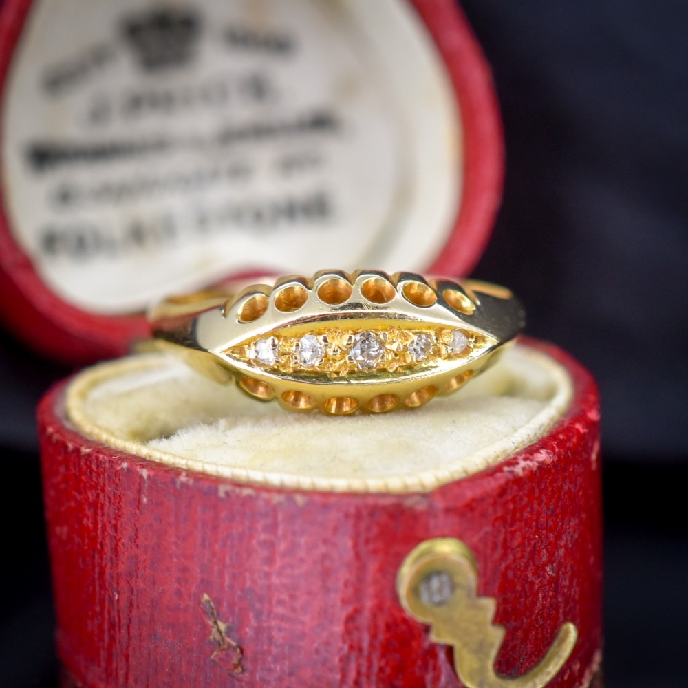 An 18ct yellow gold boat ring set with five graduated diamonds within a carved pierced gallery.